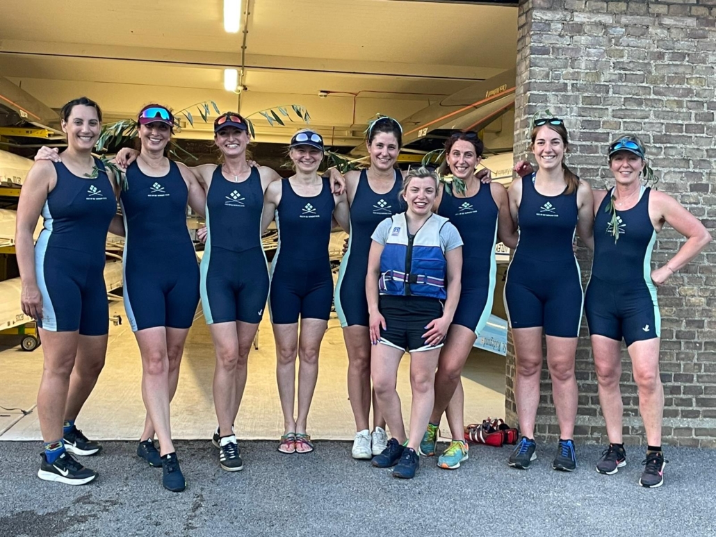 Women's eight crew on land, with willow in their hair