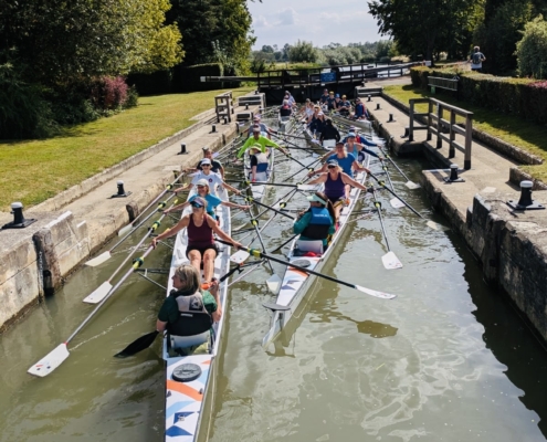 a large number of rowing boats inside a lock on the river, in the sunshine