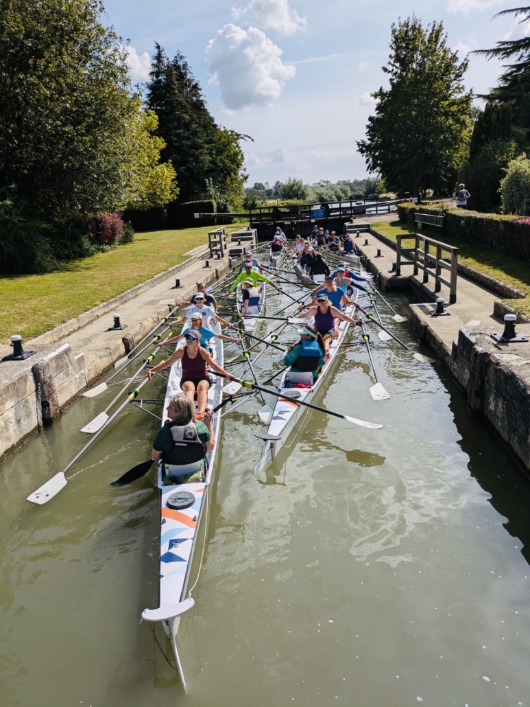a large number of rowing boats inside a lock on the river, in the sunshine